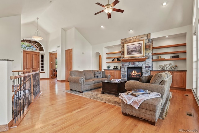11268 Bell Cross Cir, Parker, CO 80138 - living room featuring a ceiling fan, high vaulted ceiling, light wood-style flooring, arched walkways, and a stone fireplace