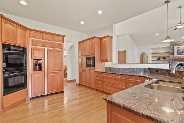 11268 Bell Cross Cir, Parker, CO 80138 - kitchen with black appliances, arched walkways, dark stone countertops, light wood-style flooring, and hanging light fixtures