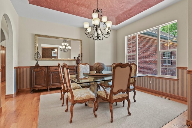 11268 Bell Cross Cir, Parker, CO 80138 - dining space with a chandelier, light wood-type flooring, a wainscoted wall, and arched walkways