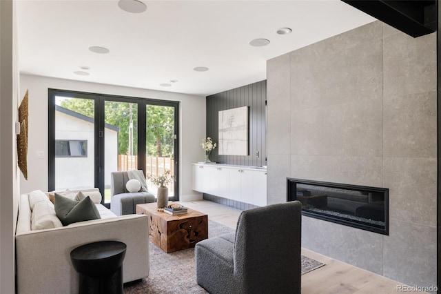 living room featuring light hardwood / wood-style floors, tile walls, and a tile fireplace