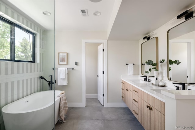 bathroom with vanity, a bath, and tile walls