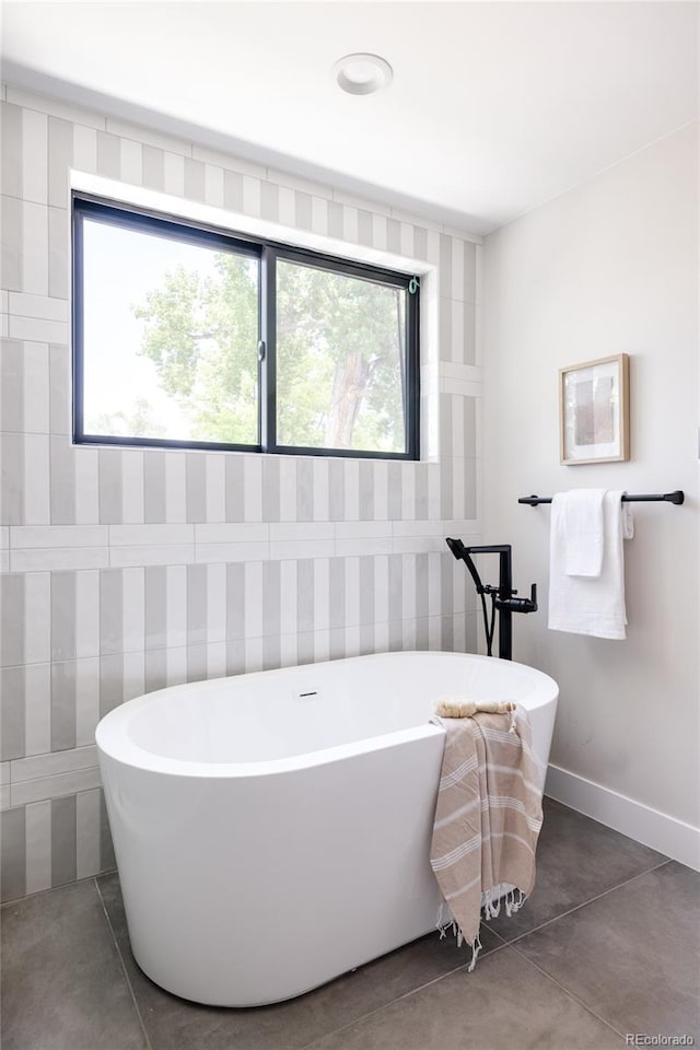 bathroom featuring plenty of natural light, a bath, and tile walls