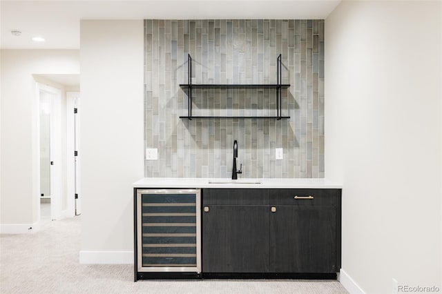 bar with sink, light colored carpet, and beverage cooler