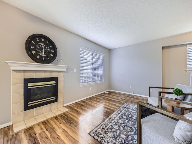5154 E 126th Ct, Thornton, CO 80241 - living area featuring wood finished floors, a tiled fireplace, and a textured ceiling