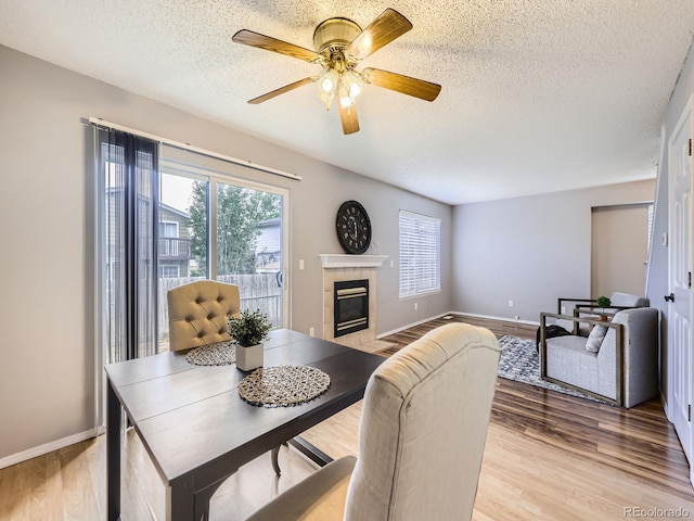 5154 E 126th Ct, Thornton, CO 80241 - dining area featuring a textured ceiling, a tile fireplace, light wood-style floors, and ceiling fan