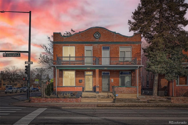 view of front facade with a balcony and brick siding
