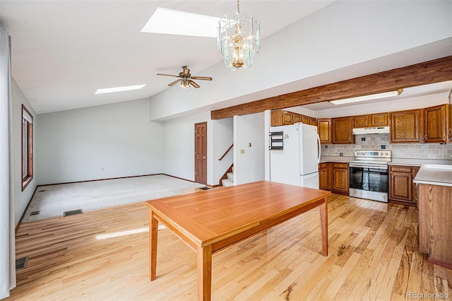 10858 Norton Ave, Conifer, CO 80433 - kitchen with brown cabinetry, under cabinet range hood, backsplash, stainless steel electric stove, and freestanding refrigerator