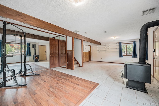 10858 Norton Ave, Conifer, CO 80433 - exercise room featuring a textured ceiling, visible vents, a wood stove, and light tile patterned floors
