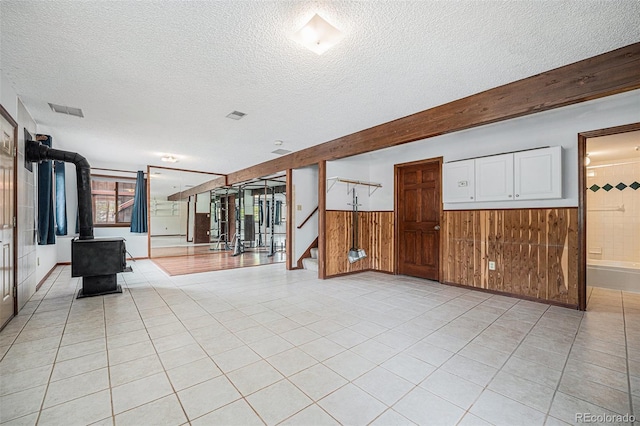 10858 Norton Ave, Conifer, CO 80433 - spare room with a wainscoted wall, a textured ceiling, wood walls, stairs, and a wood stove