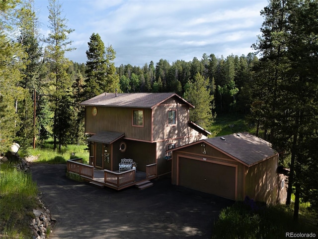 10858 Norton Ave, Conifer, CO 80433 - view of front of property featuring asphalt driveway, a wooded view, a deck, and roof with shingles