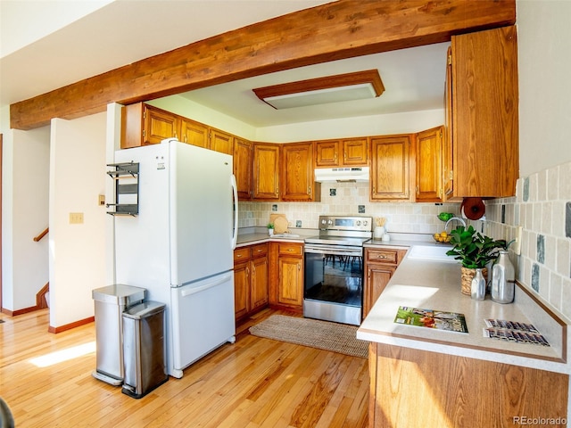 10858 Norton Ave, Conifer, CO 80433 - kitchen with stainless steel range with electric stovetop, under cabinet range hood, freestanding refrigerator, brown cabinetry, and beamed ceiling