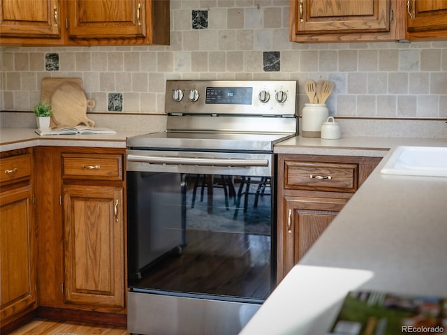 10858 Norton Ave, Conifer, CO 80433 - kitchen featuring stainless steel electric stove, light countertops, brown cabinetry, and tasteful backsplash