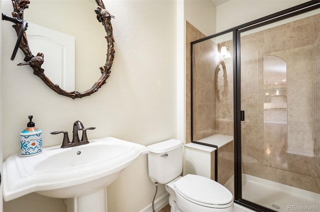 bathroom featuring sink, a shower with door, and toilet