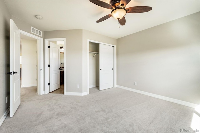 unfurnished bedroom with ceiling fan, light colored carpet, ensuite bathroom, and a closet