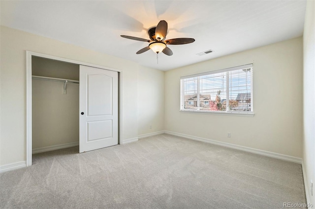 unfurnished bedroom with ceiling fan, light carpet, and a closet