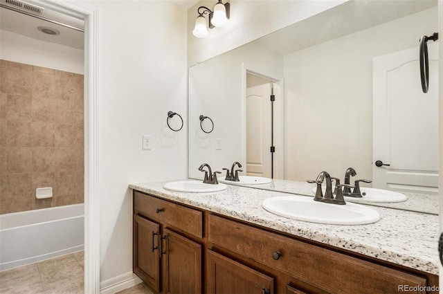 bathroom with tile patterned flooring, vanity, and tiled shower / bath