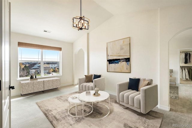 living area with light carpet, vaulted ceiling, and a notable chandelier