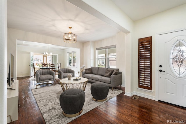 living room with dark hardwood / wood-style floors, an inviting chandelier, and plenty of natural light