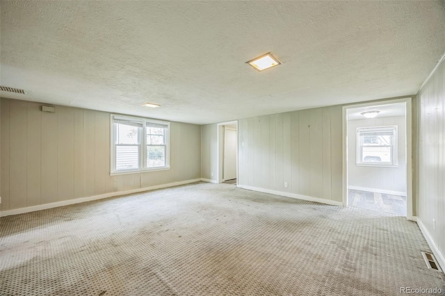 524 N 4th Ave, Sterling, CO 80751 - carpeted spare room with a textured ceiling, healthy amount of natural light, baseboards, and wooden walls