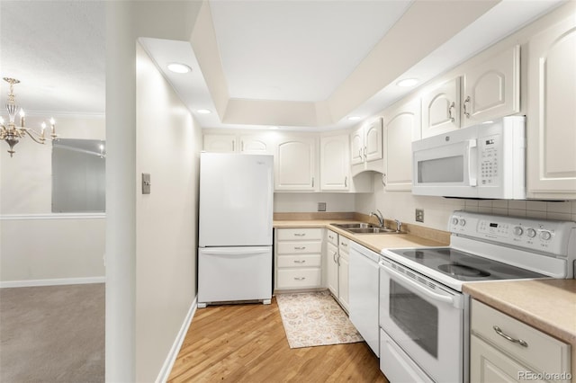 kitchen featuring decorative backsplash, a sink, light wood-type flooring, white appliances, and baseboards