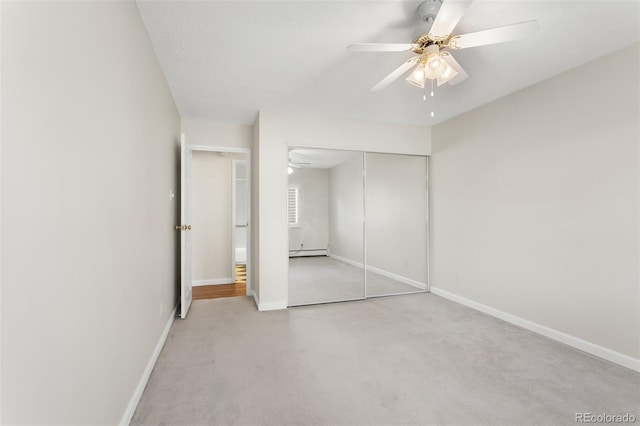 unfurnished bedroom featuring a baseboard radiator, a closet, light colored carpet, and baseboards