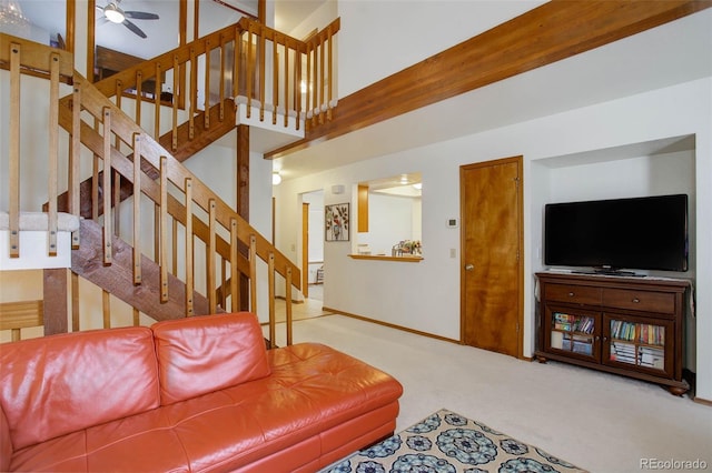 carpeted living room featuring ceiling fan and a high ceiling