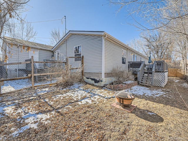 view of snowy exterior featuring an outdoor fire pit, stairs, fence, and a wooden deck