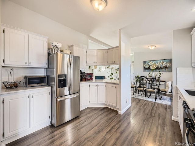 kitchen featuring vaulted ceiling, light countertops, tasteful backsplash, and stainless steel fridge