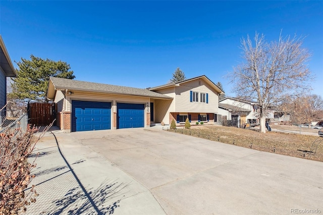 tri-level home with driveway, brick siding, an attached garage, and fence