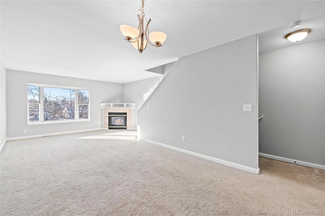 unfurnished living room with a fireplace, carpet floors, and an inviting chandelier