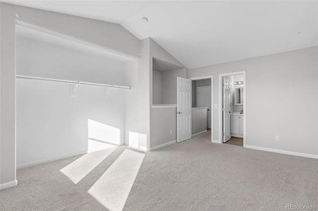 unfurnished bedroom with vaulted ceiling, light colored carpet, a closet, and ensuite bath