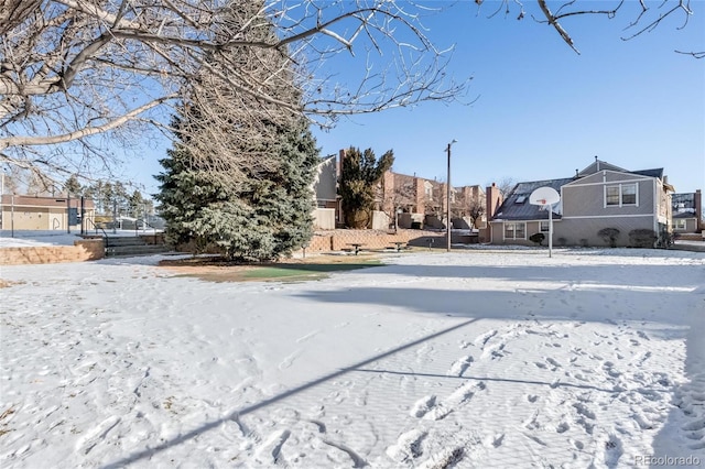 snowy yard featuring basketball court