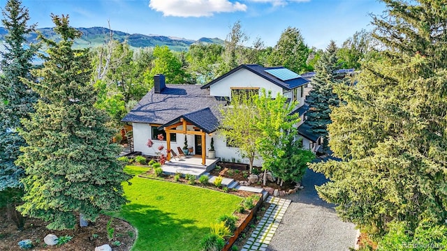 1801 Redwood Ave, Boulder, CO 80304 - view of front of property featuring a front lawn, roof mounted solar panels, a chimney, stucco siding, and a mountain view