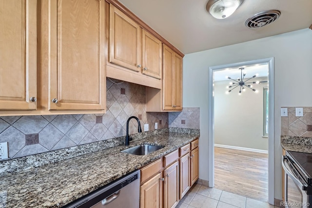 2310 Kenton St, Aurora, CO 80010 - kitchen featuring appliances with stainless steel finishes, dark stone countertops, light tile patterned floors, backsplash, and a chandelier