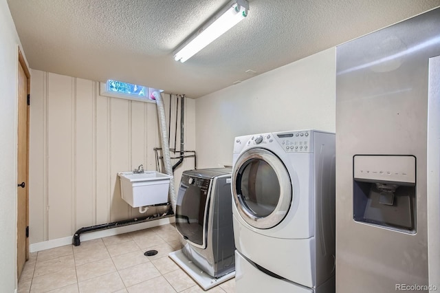2310 Kenton St, Aurora, CO 80010 - laundry room featuring washing machine and dryer, a textured ceiling, and light tile patterned floors