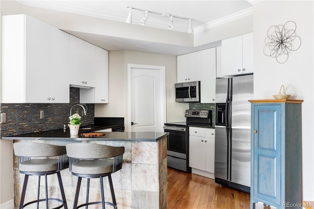 111 S Monroe St Unit B106, Denver, CO 80209 - kitchen with stainless steel appliances, dark countertops, a peninsula, rail lighting, and crown molding