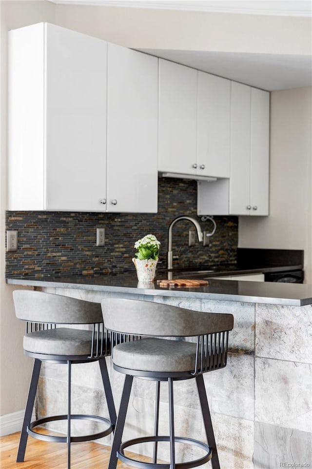 111 S Monroe St Unit B106, Denver, CO 80209 - kitchen featuring white cabinets, decorative backsplash, and light wood finished floors