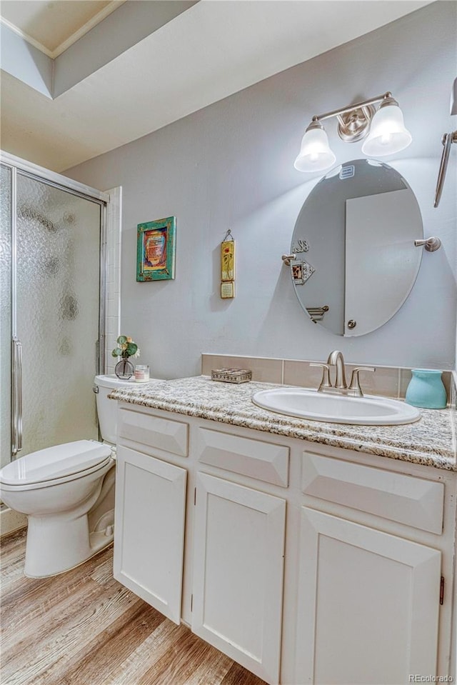 bathroom featuring vanity, a shower with door, toilet, and wood-type flooring