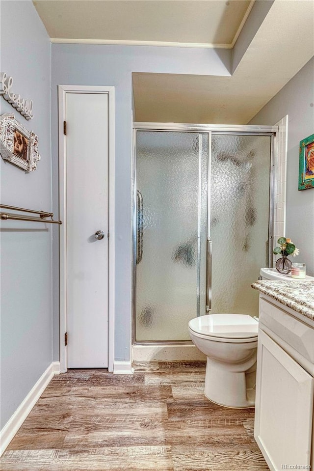 bathroom with an enclosed shower, toilet, vanity, and wood-type flooring