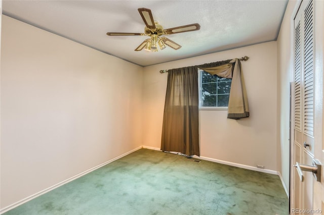 carpeted spare room featuring ceiling fan and a textured ceiling