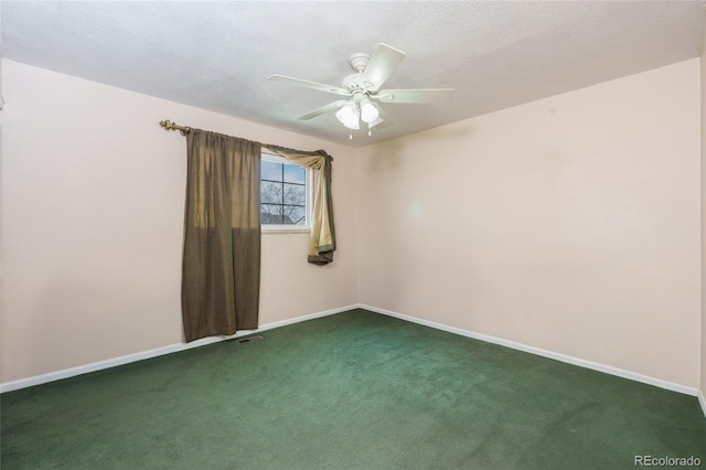 empty room featuring a textured ceiling, dark carpet, and ceiling fan