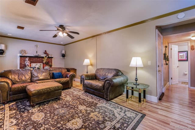 living room featuring a fireplace, ornamental molding, light wood-type flooring, and ceiling fan