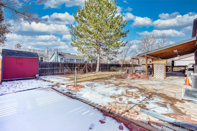 snowy yard with a patio area and a storage shed