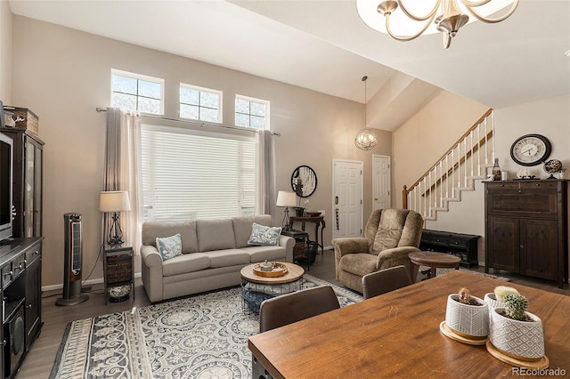 living room with a notable chandelier, lofted ceiling, and hardwood / wood-style flooring