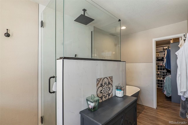 bathroom with a textured ceiling, a shower with door, and hardwood / wood-style flooring