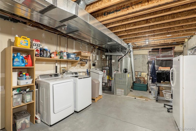 basement featuring washer and clothes dryer, white refrigerator, water heater, and heating unit