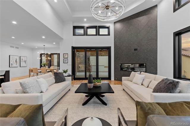 8103 Raphael Ln, Littleton, CO 80125 - living room featuring light wood-style floors, a chandelier, a high ceiling, and recessed lighting