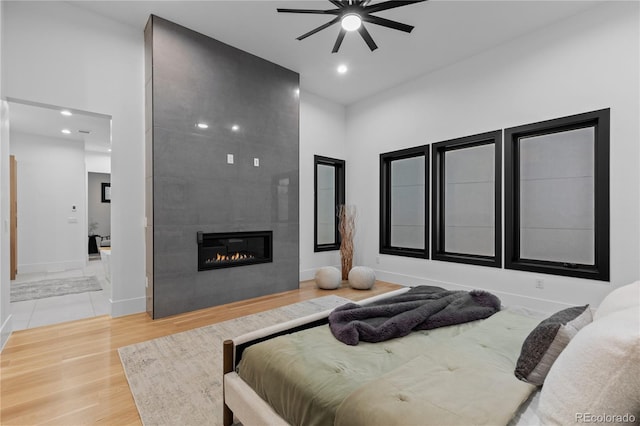8103 Raphael Ln, Littleton, CO 80125 - bedroom featuring a tile fireplace, wood finished floors, a high ceiling, baseboards, and recessed lighting