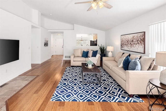 living room with a ceiling fan, vaulted ceiling, wood finished floors, and visible vents
