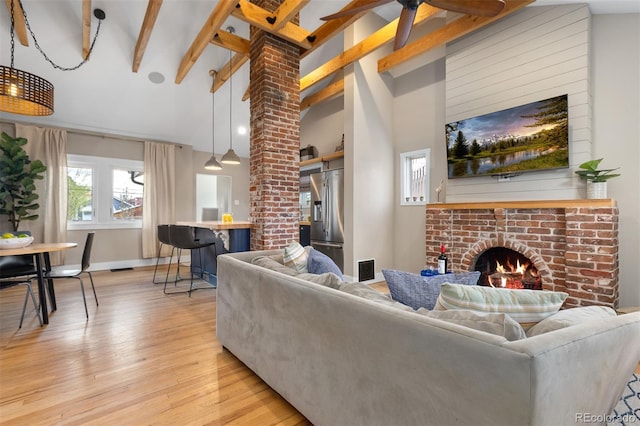 living area with high vaulted ceiling, light wood finished floors, beamed ceiling, a fireplace, and visible vents